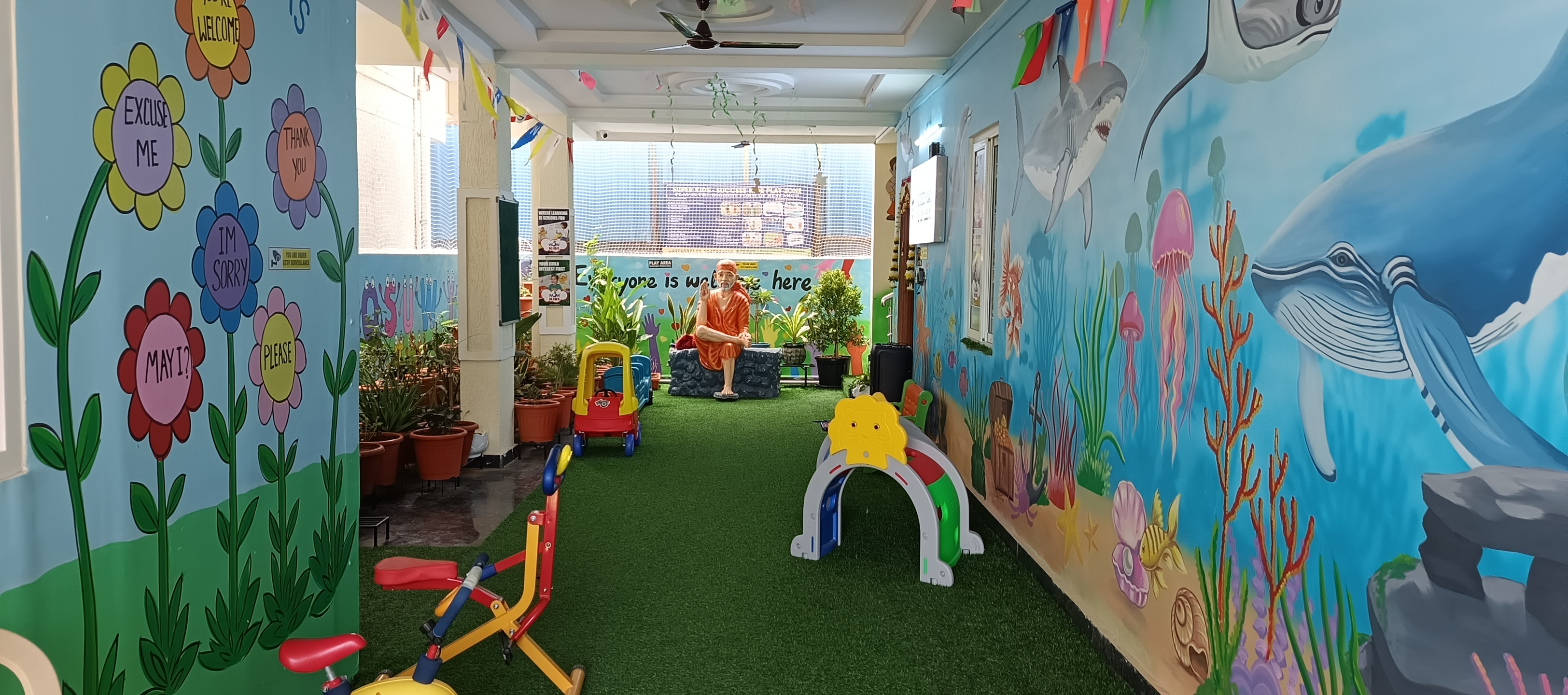 Colorful indoor play area with ocean murals, artificial turf and playground equipment