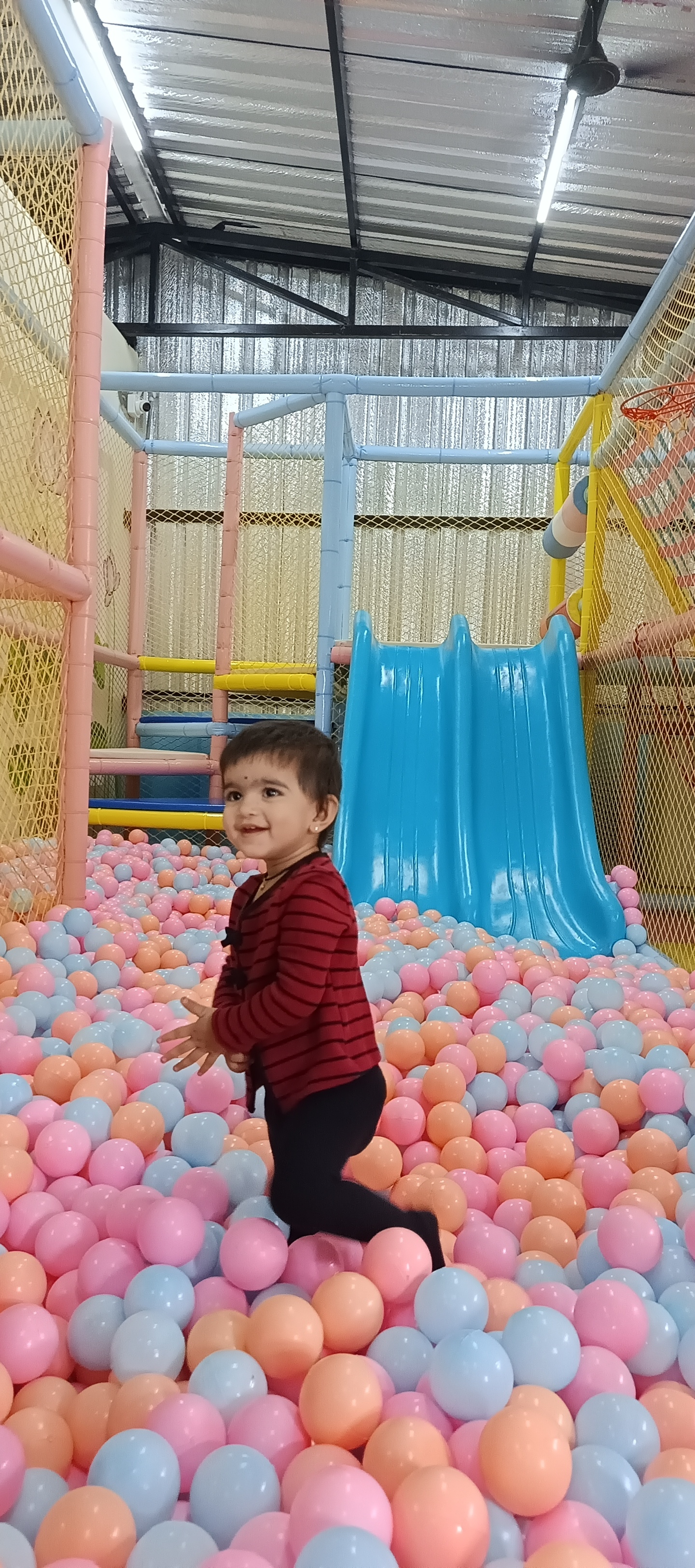 Child playing happily in colorful ball pit pool