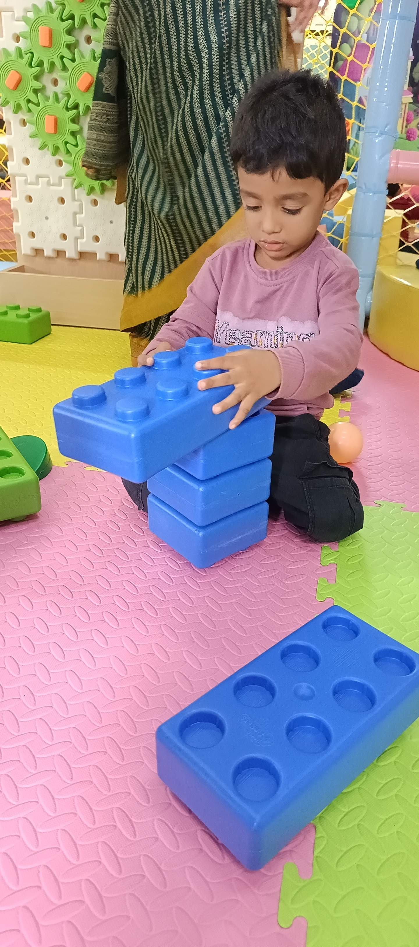 Toddler building creative structures with oversized blue blocks