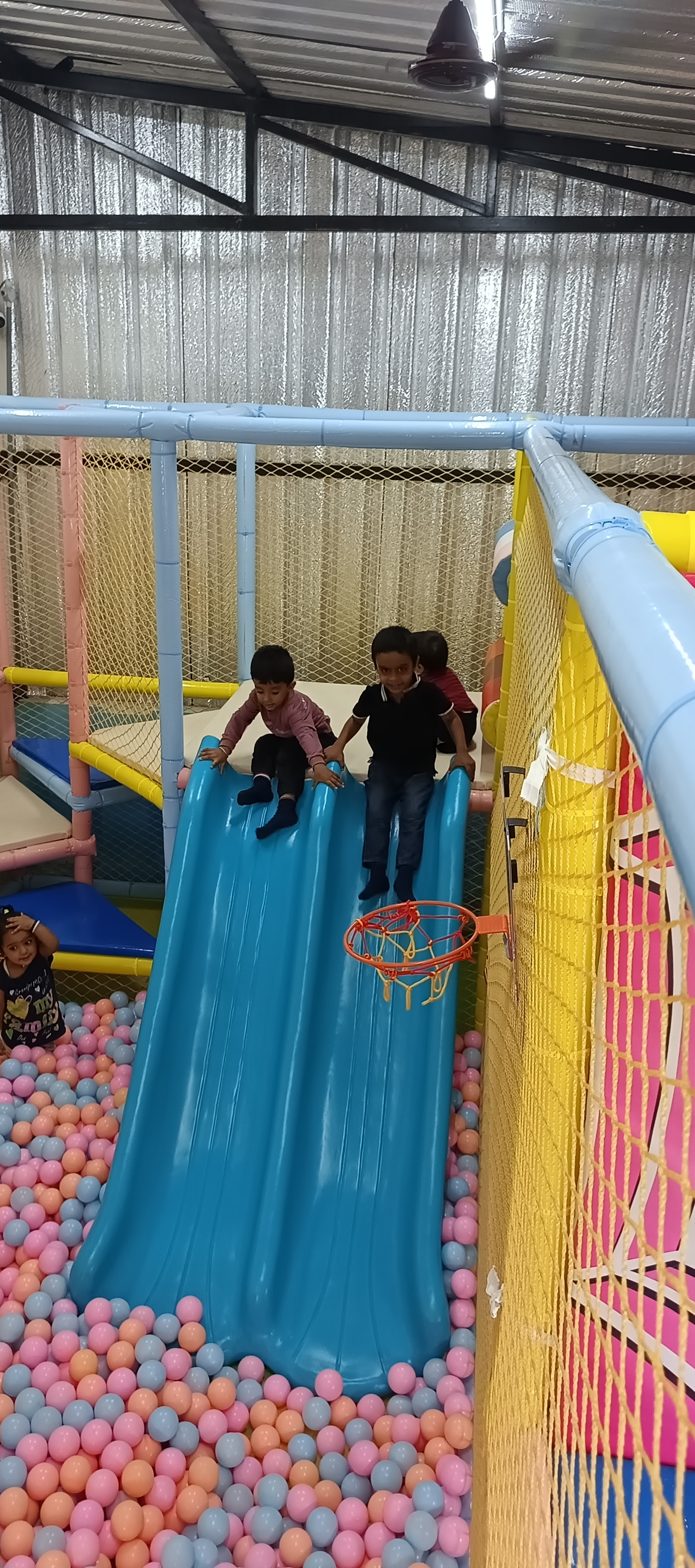 Children sliding down blue double slides into ball pit